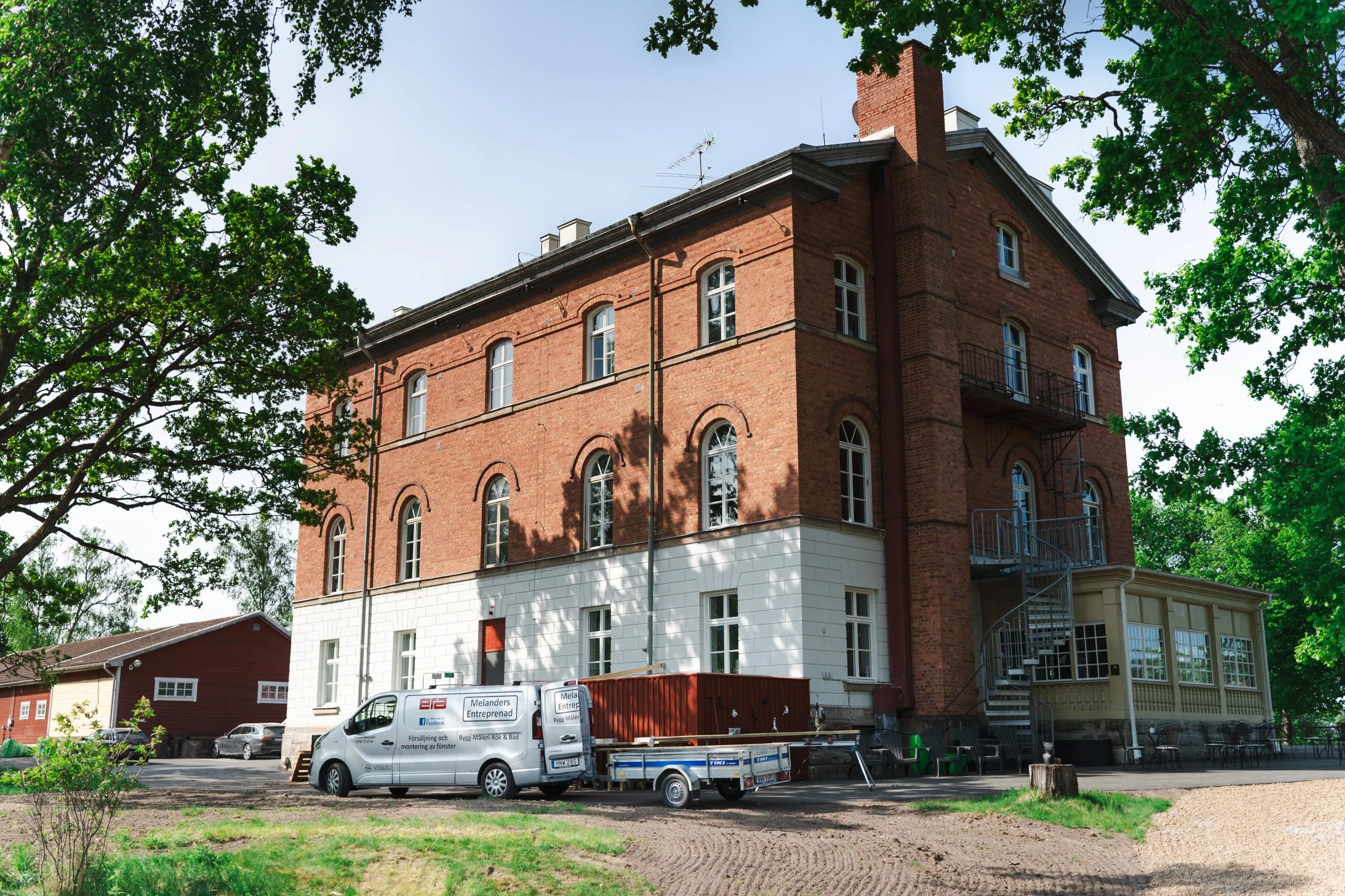 Melanders Entreprenads servicebil vid en pågående renovering av en äldre tegelbyggnad